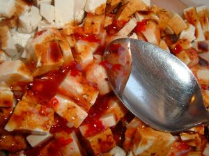Marinating small tofu cubes with chili sauce and vinegar
